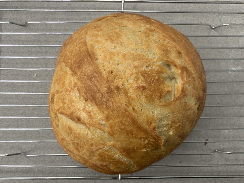 A freshly baked loaf of bread resting on a wire rack.