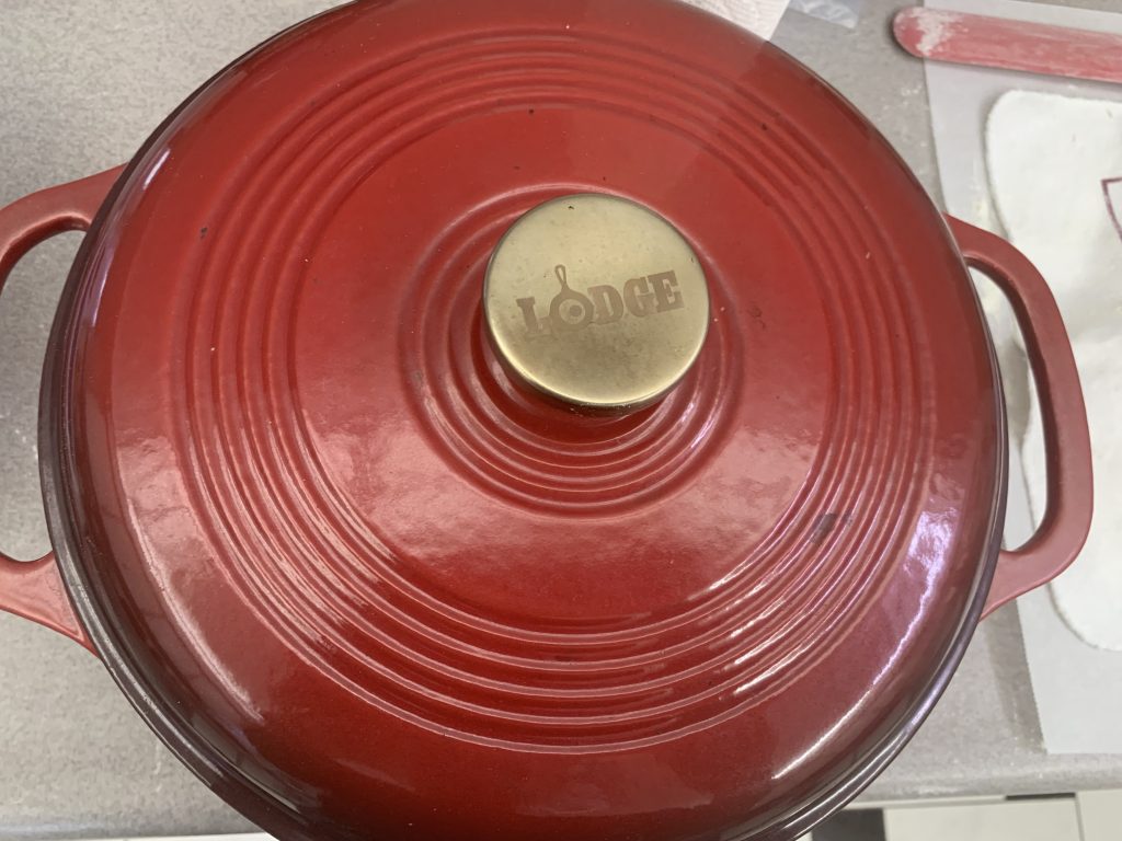 A Cast Iron Dutch oven with “Lodge” written on the lid.